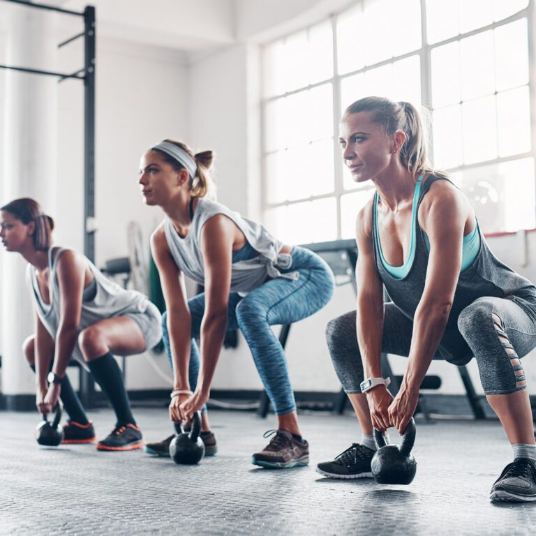 Group fitness class performing kettlebell exercises during circuit training at The Workout Club Salem gym