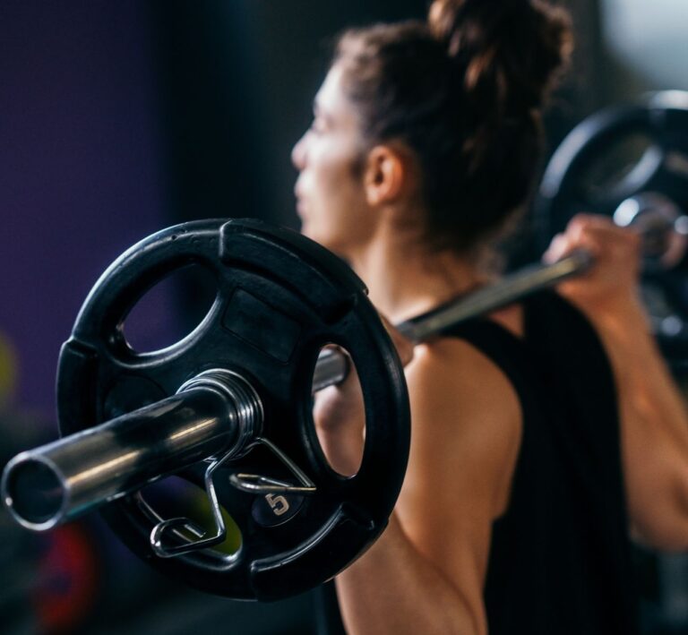 Woman lifting barbell in a Les Mills BodyPump class at The Workout Club Salem gym