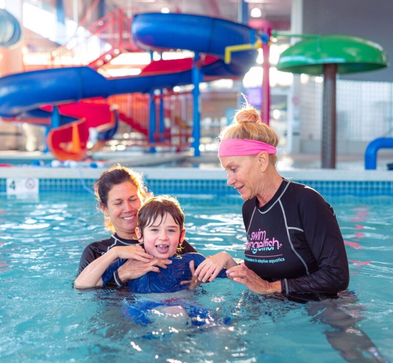 Swim instructor helping kids practice arm strokes during swim lessons at The Workout Club Salem NH indoor pool