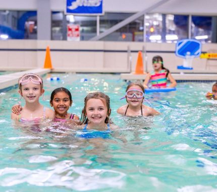 Group of kids smiling in the indoor pool during a birthday party at The Workout Club Salem NH