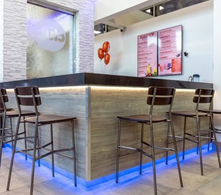 Modern shake bar counter with tall stools and illuminated base near the front desk at The Workout Club Salem NH