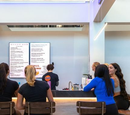 Members sitting at the shake bar at The Workout Club Salem NH looking at the smoothie menu while staff prepares drinks