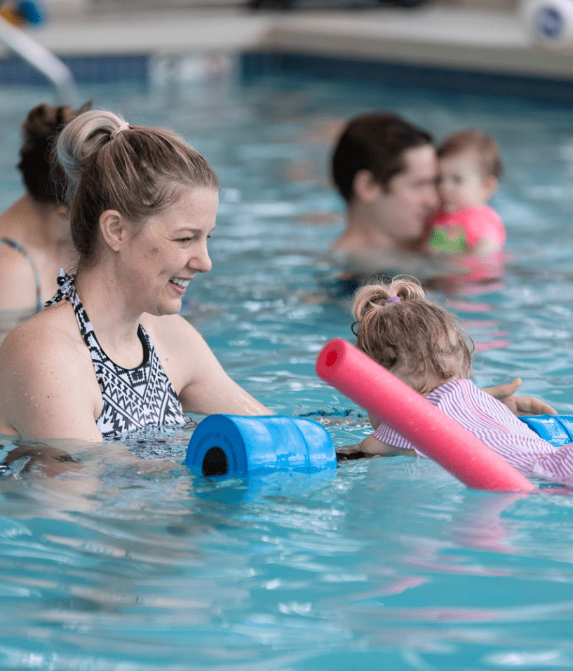 Parents and toddlers enjoying a swim class at The Workout Club’s indoor pool, promoting family-friendly fitness and fun.