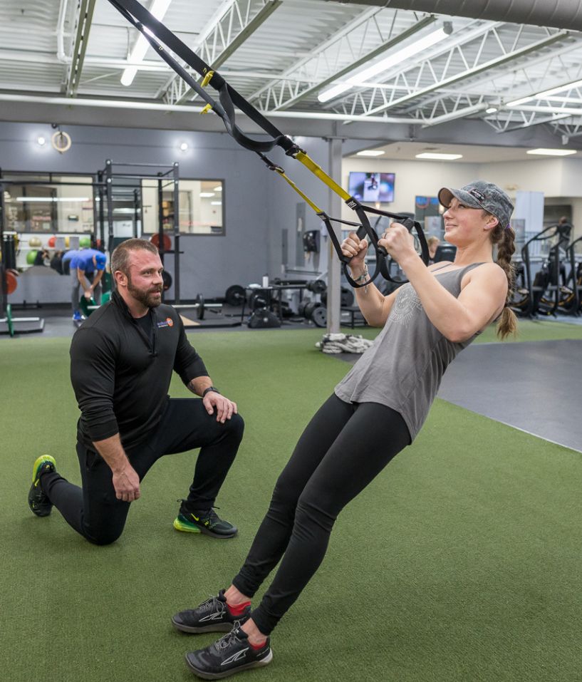 Personal trainer coaching a woman through TRX suspension training at The Workout Club’s state-of-the-art fitness center.