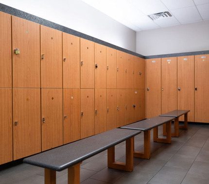Clean and spacious private locker room at The Workout Club featuring secure wooden lockers and bench seating.