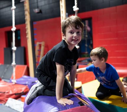 Kids playing and climbing through a colorful ninja-style obstacle course at The Workout Club’s dynamic day camp.